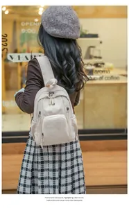 Close-up of stylish beige large capacity nylon backpack worn by a model near a cafe
