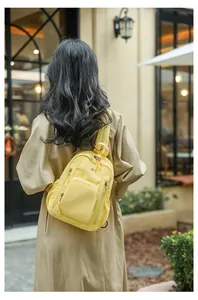 Outdoor shot of a model wearing a vibrant yellow nylon backpack with multiple zipper pockets