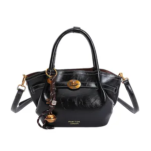 Minimalist black dumpling tote bag in glossy leather with retro metal lock and strap