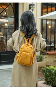 Outdoor shot showing back view of mustard yellow nylon backpack with multi-pocket design