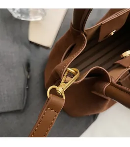 Detail of premium golden hardware and brown suede texture on a stylish pleated handbag