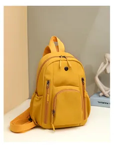 Detail view of a stylish yellow nylon backpack featuring multiple pockets and top handle