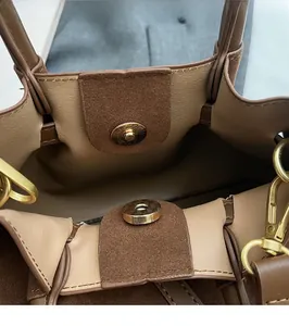 Close-up of a dark brown pleated handbag showing the magnetic clasp and gold hardware