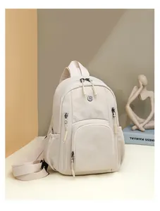 Detailed view of cream nylon backpack featuring front zip pocket and metal logo detail