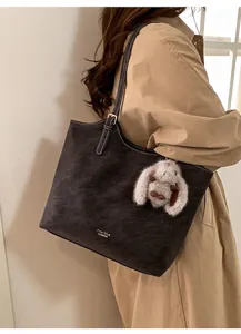 Dettaglio borsa tote vintage marrone con logo dorato e ciondolo coniglio morbido