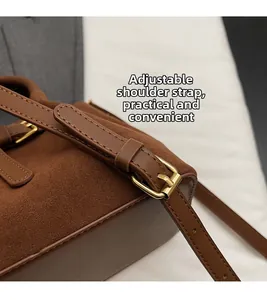 Detailed close-up of brown suede bag showing the adjustable strap with gold metal buckle
