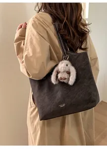 Dettaglio della borsa tote vintage con cuciture a contrasto e ciondolo a forma di coniglio