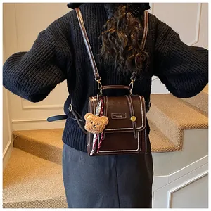 Close-up of vintage brown leather backpack with contrast stitching and bear charm