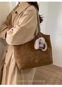 Dettaglio borsa tote in pelle scamosciata marrone con ciondolo a coniglio e logo vintage