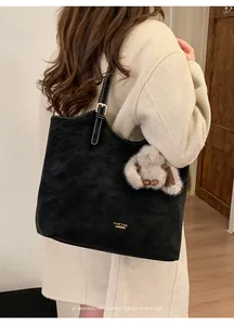 Dettaglio della borsa tote in pelle scamosciata nera con fibbia dorata e ciondolo a coniglio