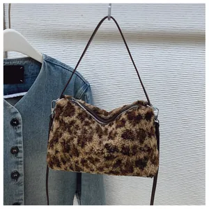 Détail d'un sac en peluche léopard avec fermeture éclair et fine bandoulière en cuir