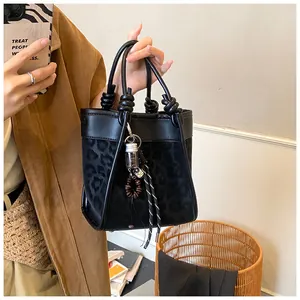Détail du sac seau léopard avec poignée nouée et charmant pendentif décoratif chic