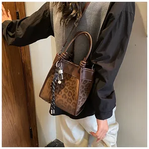 Détail du sac seau léopard avec breloque en corde tressée et bordure en cuir marron
