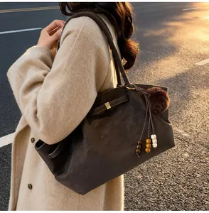 Detail of dark brown suede tote bag with plush fur ball and wooden bead charms