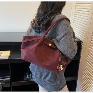 Close-up of wine red suede tote bag with decorative wooden beads and tassel charms