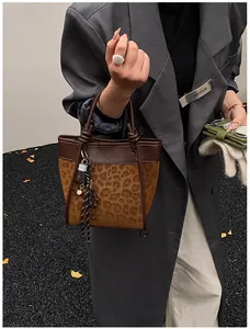 Détail du sac cabas imprimé léopard avec poignées nouées et accessoires de charme stylés