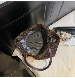 Detail view of leopard print tote bag with striped lining and brown leather handle