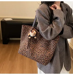 Detail of leopard print tote bag with plush bear charm and black shoulder strap