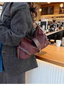 Détail du sac cabas en daim bordeaux avec lanières en cuir marron et boucles vintage