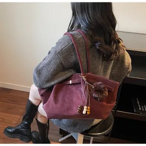 Detail view of burgundy faux suede tote bag with decorative bead tassel and fur charm