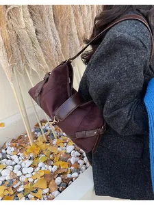 Détail d'un grand cabas en daim marron avec lanières en cuir lisse et boucles dorées