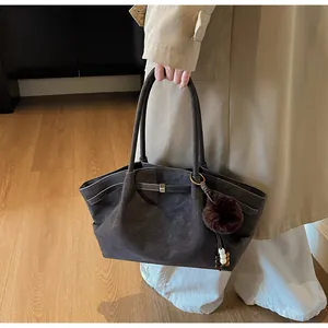 Detail of suede tote bag with decorative pompom and bead charm in coffee brown