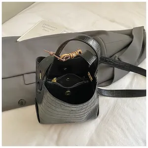 Detail view of black crocodile pattern bucket bag with magnetic closure and inner pocket