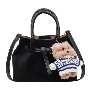 Minimalist black pleated tote bag with round handles and a cute bear bag charm accessory