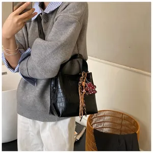 Detail of black crocodile embossed bucket bag with leather fringe and heart charm