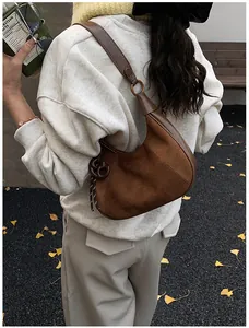 Dettaglio borsa a sella in pelle scamosciata marrone con anello metallico vintage e tracolla