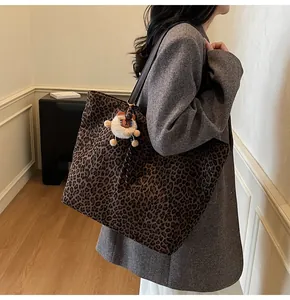 Detail shot of large leopard print tote bag with brown shoulder strap and plush bear charm