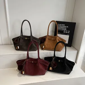 Retro suede tote bags in four colors with pompom charms on marble display