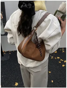 Dettaglio di una borsa a spalla vintage in pelle scamosciata marrone con ciondoli moda