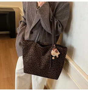 Detailed view of leopard print tote bag with brown leather straps and cute plush charm