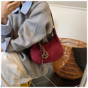 Dettaglio borsa hobo in pelle scamosciata bordeaux scuro con ciondolo e cordino intrecciato