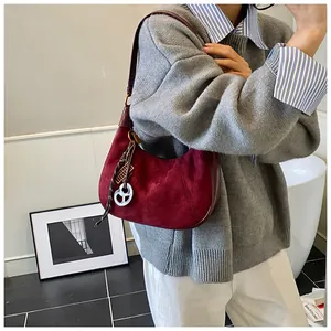 Dettaglio borsa hobo bordeaux con ciondolo logo indossata da modella in maglione di maglia
