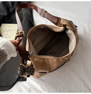 Detail of brown suede tote bag featuring a gold zipper and leopard print bow charm