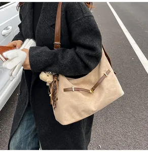 Detail of beige tote bag with brown straps, plush bear charm and leopard scarf accent