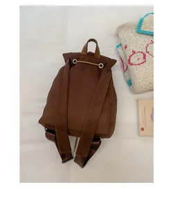 Detalle de la mochila vintage de ante marrón con correas ajustables y asa de cuero