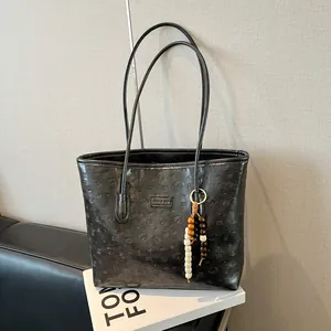 Large black embossed tote bag with puppy patterns and colorful beaded charm accessory