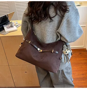 Detail of large dark brown suede hobo bag with metal buckle and cute doll charm