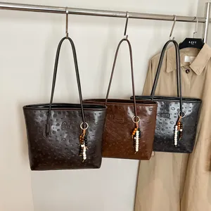 Three minimalist large capacity tote bags in coffee, brown, and black hanging from a rack