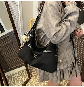 Detail view of black nylon tote bag with cute plush bear pendant on model