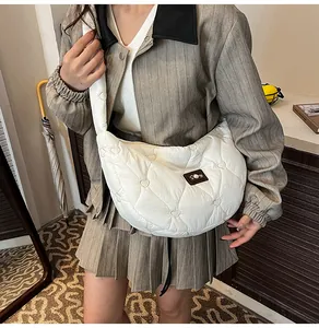 Detail of white quilted half-moon bag featuring heart embroidery and pearl leather tag