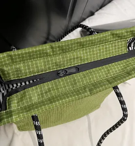 Detail view of smooth metal zipper and black white rope handles on green checkered tote