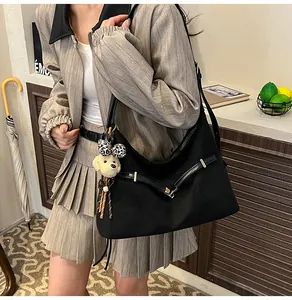 Detail of black tote bag with matte texture, buckle straps, and plush puppy pendant charm