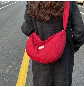 Close-up of red heart-quilted puffer crossbody bag worn over a dark winter coat