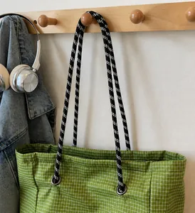 Detail of green plaid canvas tote bag featuring durable black and white woven rope handles