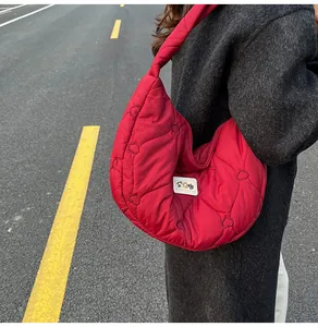 Close-up of red quilted crescent bag with heart embroidery and puffy cloud design