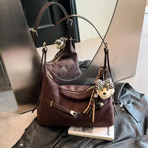 Brown suede tote bag with leather straps and bear pendant shown in a mirror reflection